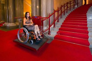 joven usando sube escaleras en escalera con alfombra roja