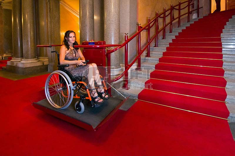 joven usando sube escaleras en escalera con alfombra roja